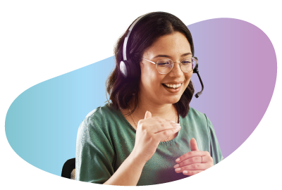 lady wearing glasses and t shirt with a headset smiling at a computer screen